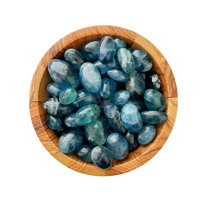 A round wooden bowl filled with Blue Fluorite Tumbled Stones of varying sizes, displayed against a white background. The stones feature various shades of blue, ranging from deep to light hues, with some exhibiting subtle white streaks and patterns—an exquisite addition to any gemstone collection.