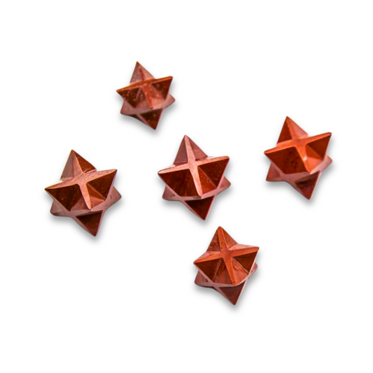 Five Mini Red Jasper Merkaba, reddish-brown, star-shaped objects with textured surfaces are scattered randomly on a white background. Each geometric, three-dimensional star resembles Red Jasper and evokes the grounding energy of the root chakra.