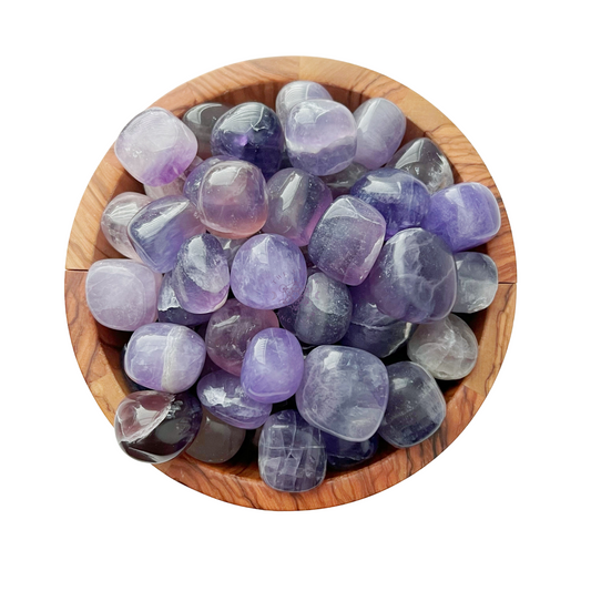 A wooden bowl filled with polished, rounded Lavender Yttrium Fluorite Tumbled Stones in varying shades of purple. The stones have a glossy finish and display a range of hues from light lavender to deep violet, each one celebrated for its metaphysical properties that promote mental clarity.