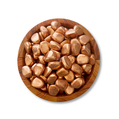 A wooden bowl filled with shiny, polished Copper Nugget Tumbled Stones is centered on a white background. These copper tumbled stones have a smooth, glossy finish and varying shapes, reflecting light to accentuate their metallic luster, perfect for chakra healing and energy transfer.