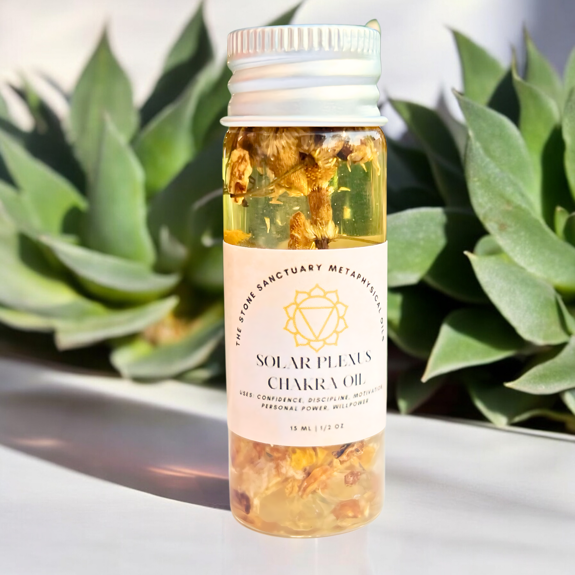 A small bottle of Solar Plexus Chakra Oil rests among succulent plants. The bottle holds yellow liquid infused with floating herbs and flowers. Its label features a yellow-chakra symbol along with the product's name, highlighting its benefits for promoting self-empowerment and confidence.