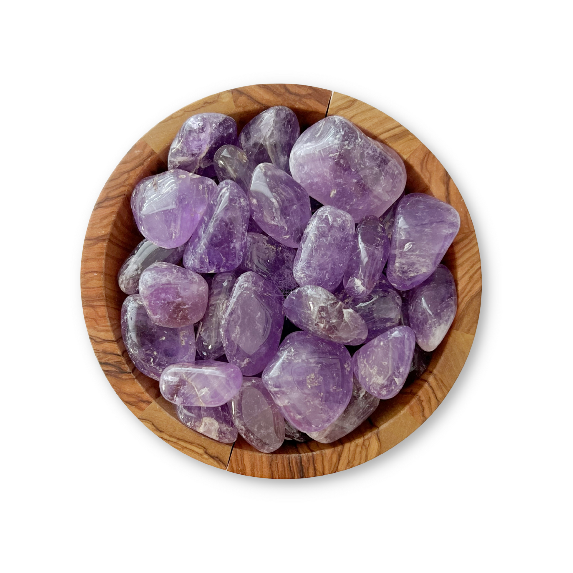 A wooden bowl filled with Amethyst Tumbled Stones (Brazil) is displayed on a white background. These smooth, shiny stones, in varying shades of purple, are known for their psychic protection and ability to relieve stress. The bowl itself has a natural wood grain pattern that complements the beauty of the amethysts.