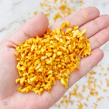 A packet of Orange Peel is shown in front of a marble mortar and pestle. More orange peel pieces fill a glass goblet in the background. The packet label indicates uses for divination, love, luck, and money, highlighting its metaphysical properties in spiritual rituals.