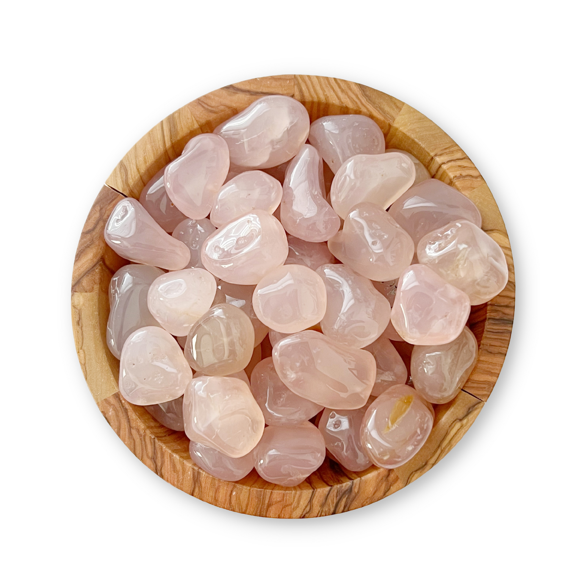 A wooden bowl filled with smooth, polished Pink Chalcedony Tumbled Stones, known as healing crystals for emotional trauma, set against a white background. The stones are pale pink and semi-translucent, varying slightly in shape and size.