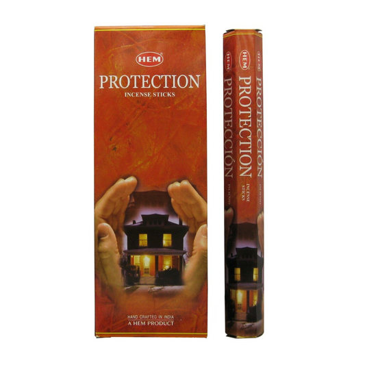 A rectangular box and a cylindrical tube of Protection Incense Sticks. The packaging features an image of a house being shielded by two hands. The text on the box reads "Protection Incense Sticks." Perfect for enhancing your meditation or yoga sessions, the product is handcrafted in India.