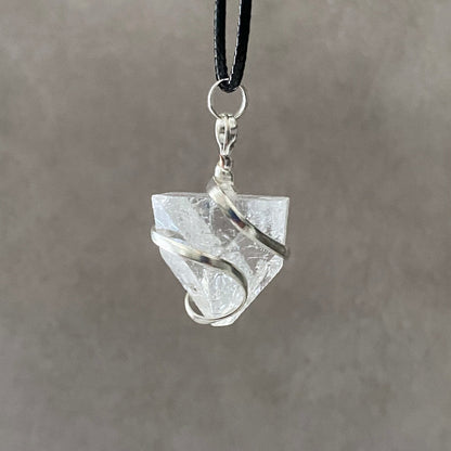 A Raw Apophyllite Pendant is wrapped with silver wire and suspended from a black cord against a plain background, enhancing high vibrational energies for the crown chakra.