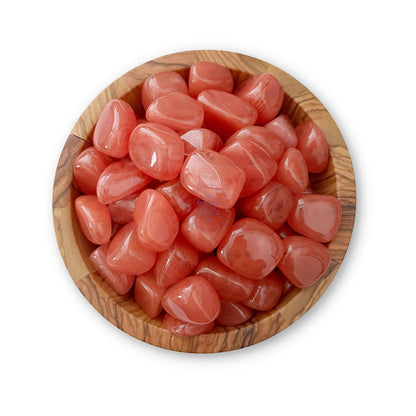 A wooden bowl filled with Cherry Quartz Tumbled Stones, known for their emotional healing properties. The orange-red stones have a smooth, shiny surface and are of various sizes. The bowl sits on a white background, evoking a sense of romantic love and tranquility.