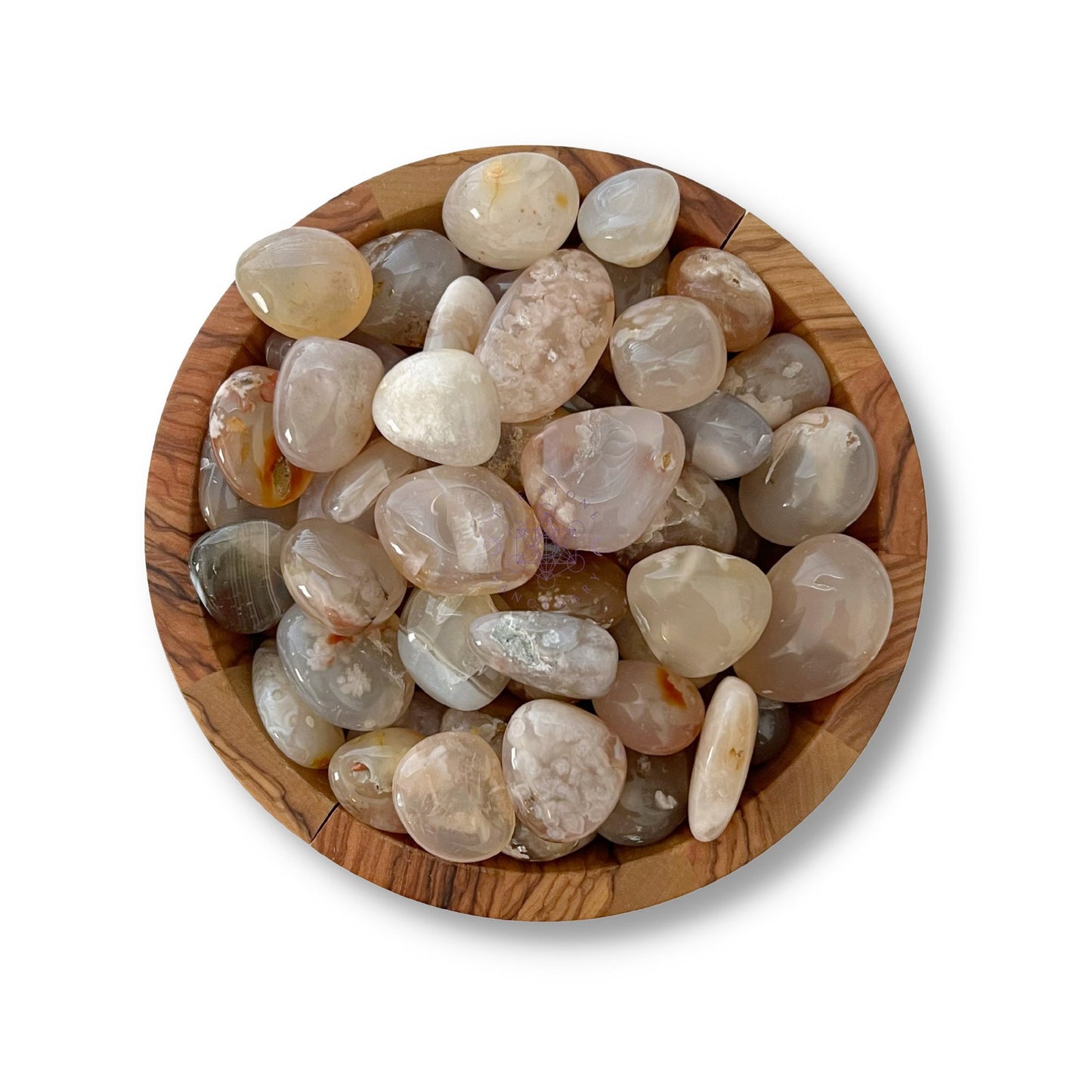 A wooden bowl filled with polished, translucent Flower Agate Tumbled Stones of various sizes and muted colors, including shades of beige, brown, and gray, sits on a plain white background.