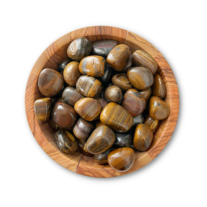 A wooden bowl filled with polished, round Tiger Iron Tumbled Stones exudes a blend of dark brown and golden striped patterns with a glossy finish. These Tiger Iron Tumbled Stones harness grounding Earth energy, enhancing physical vitality while resting on a plain white background.