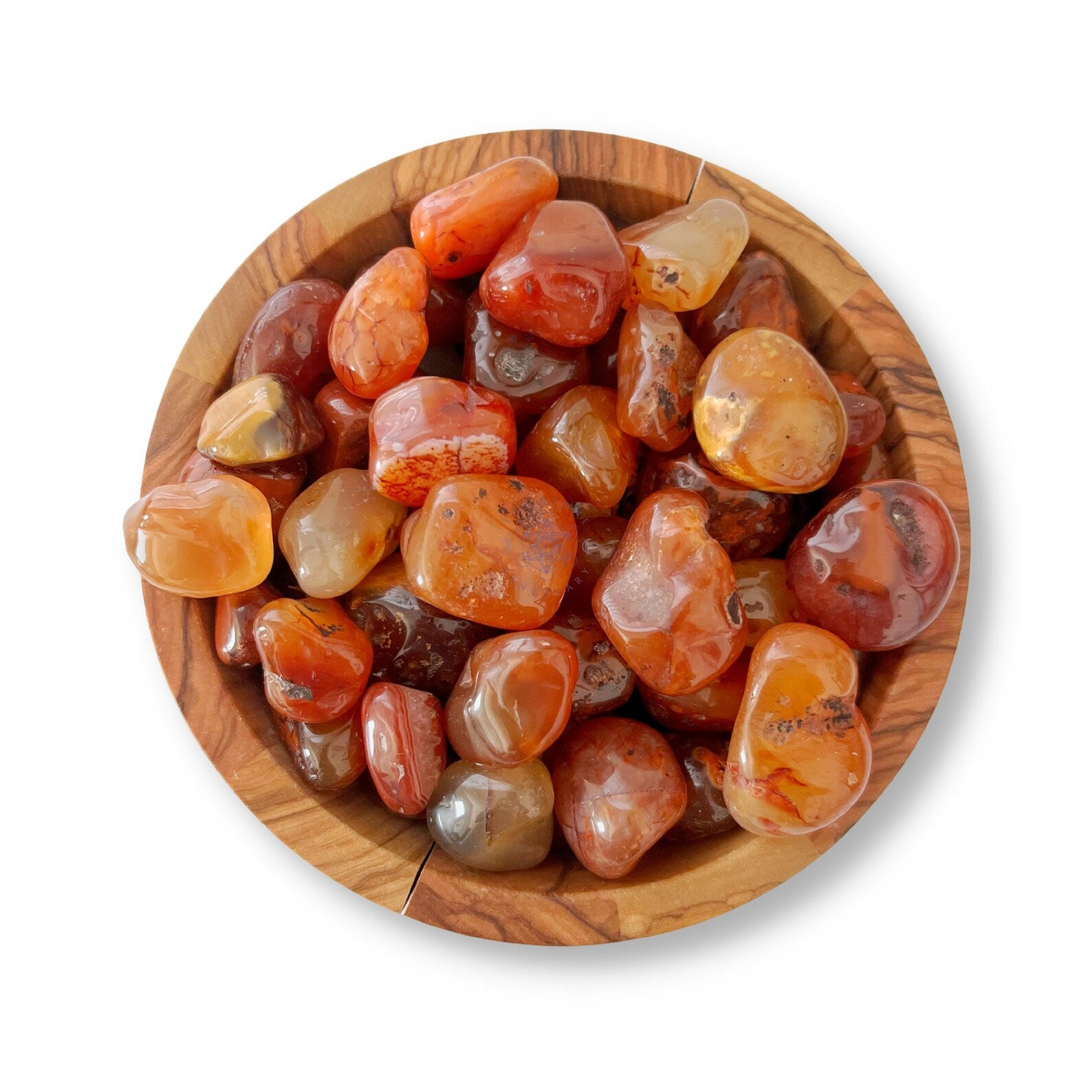 A wooden bowl filled with polished, multi-colored agate stones, including vibrant Carnelian Tumbled Pebble. These stones, in various shades of red, orange, and brown with unique patterns and inclusions, are known to enhance creativity and endurance. The bowl sits on a pristine white background.