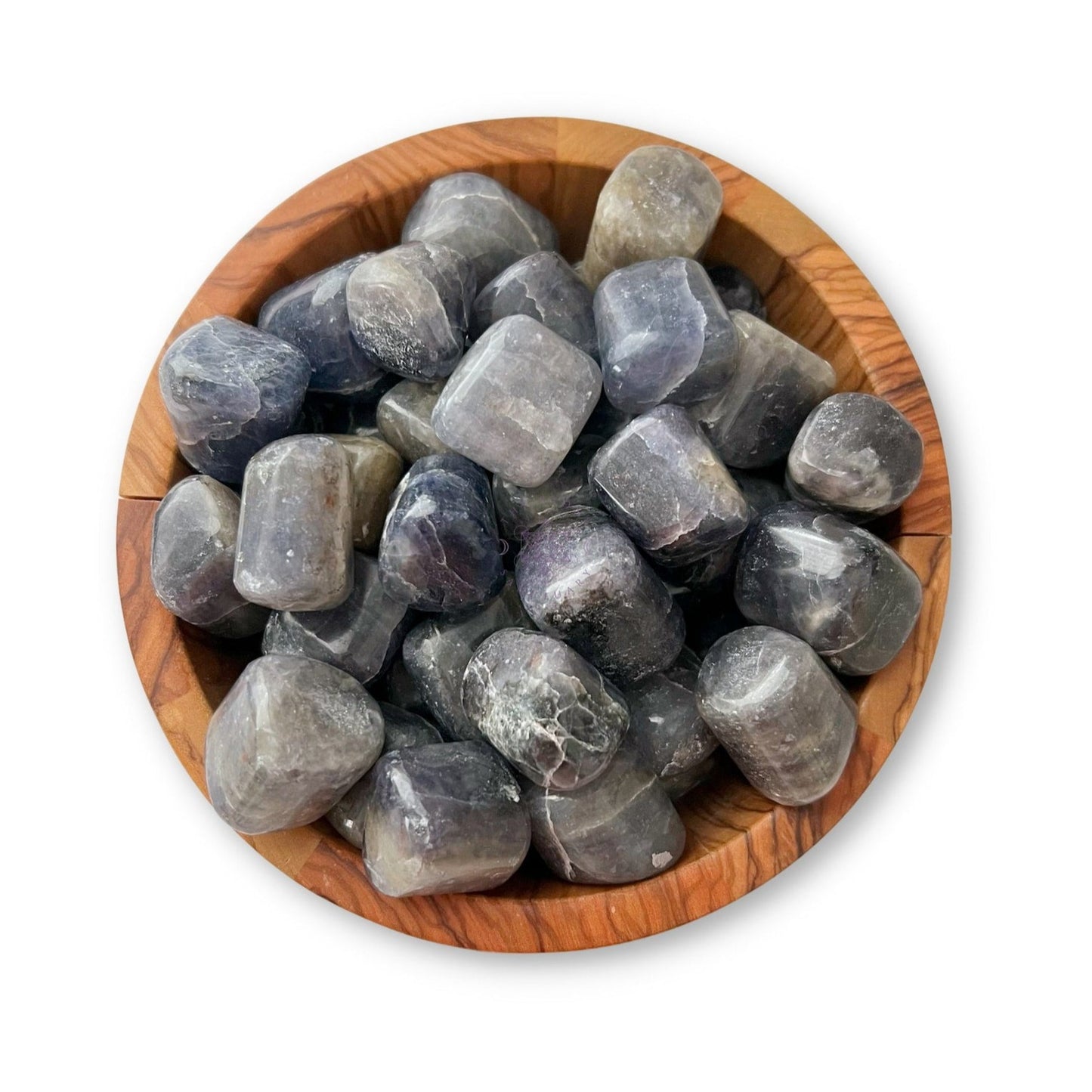 A wooden bowl filled with smooth, polished Iolite Tumbled Stones. The tumbled gemstones have a glossy finish and varying shades of blue and gray, creating a striking and natural look. The bowl has a natural wood grain, complementing the earthy tones of the vision stones.