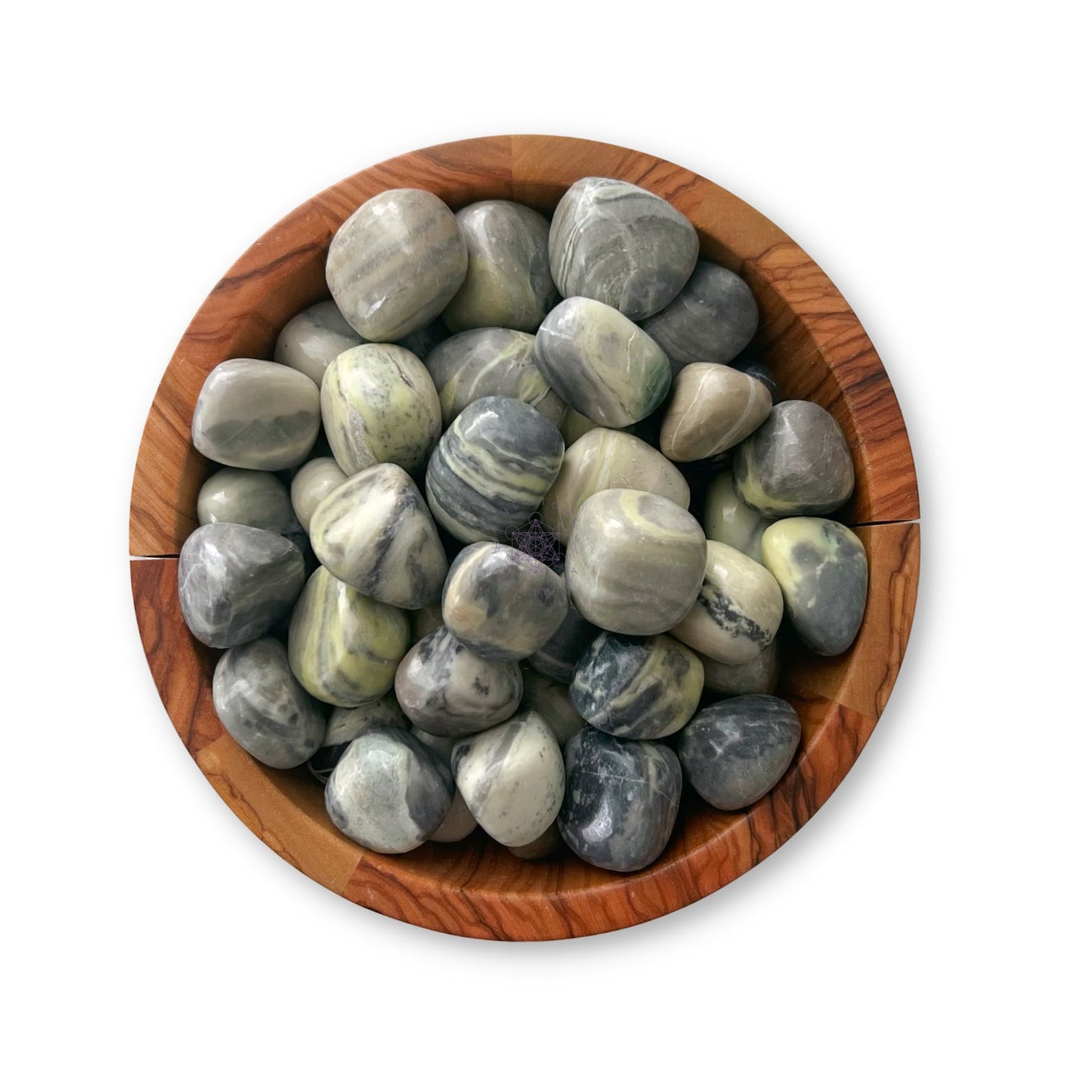 A wooden bowl filled with smooth, polished green and gray stones of various sizes. The stones, resembling Infinite Serpentine Tumbled Stones, have a marbled texture with swirls of green, gray, and white. The bowl sits on a white surface.