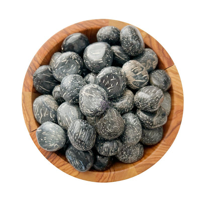 A wooden bowl is filled with smooth, polished Crinoid Fossil Tumbled Stones. The stones are speckled with white, resembling stars scattered across a night sky. The bowl's natural wood grain provides a contrasting backdrop to the glossy stones, evoking a sense of spiritual growth and tranquility.