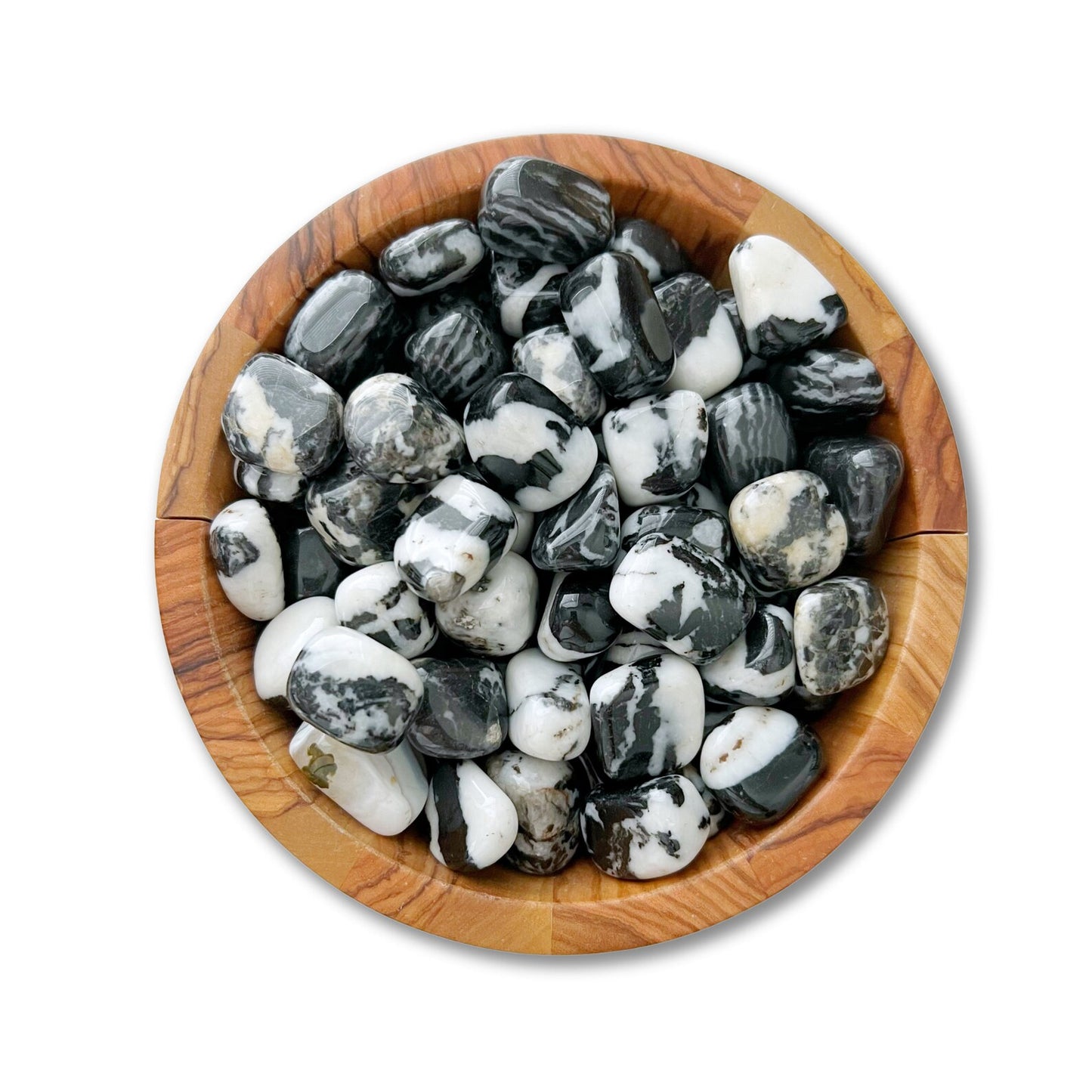 A wooden bowl filled with Zebra Jasper Tumbled Stones, exhibiting black and white marbled stones against a white background. The stones vary in size and have a glossy finish, showcasing intricate patterns that offer both beauty and stress relief.