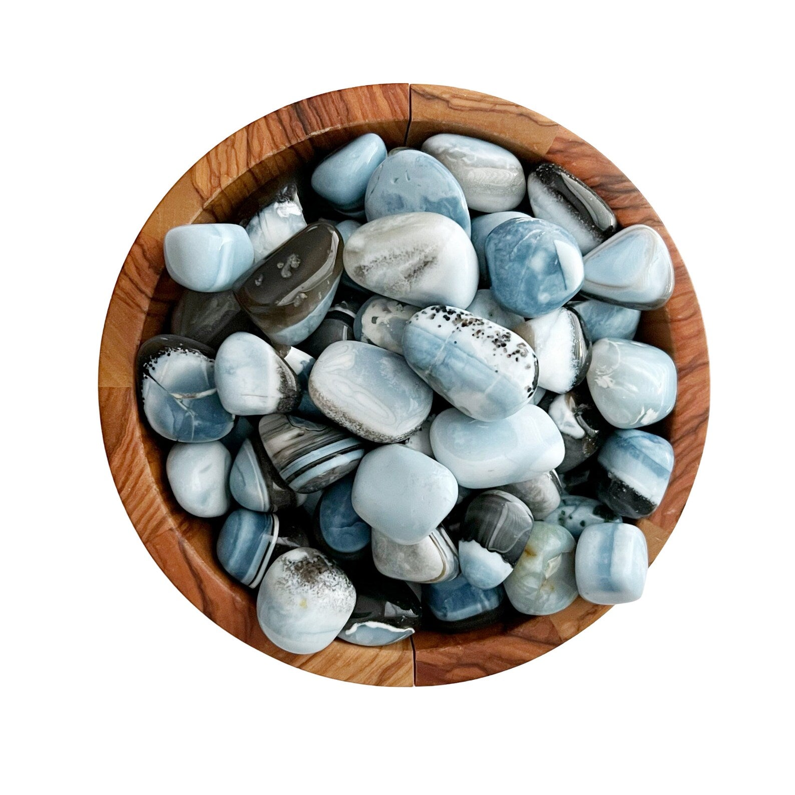 A wooden bowl filled with Owyhee Blue Opal Tumbled Stones of various shades and sizes. The stones have a smooth, glossy finish and exhibit streaks and patterns in different hues of blue, white, and some subtle gray tones. Known for their use in healing crystal metaphysical practices, the bowl sits against a white background.