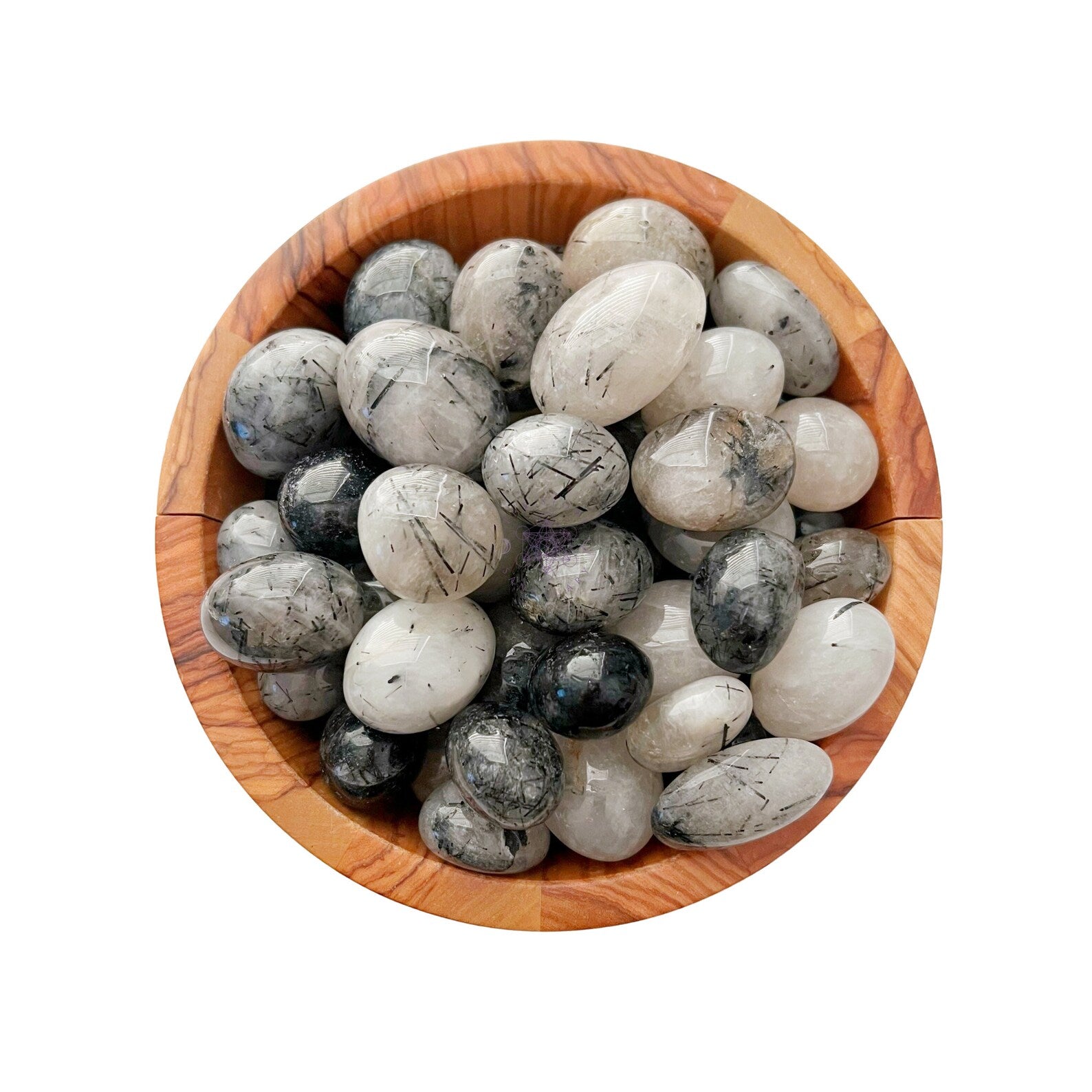 A wooden bowl filled with smooth, polished stones of various shades of grey, black, and white. The stones, including exquisite Black Rutilated Quartz Tumbled Stones, have unique patterns and striations, adding an artistic touch. Known for their metaphysical properties, they contrast beautifully with the bowl’s grain.