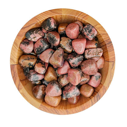 A wooden bowl filled with polished Raspberry Rhodonite Tumbled Stones. The stones have a mix of pink, red, and black colors with veining patterns, and they appear smooth and shiny. Known for their Heart chakra benefits, these gemstones sit beautifully in the bowl's natural wood grain texture.