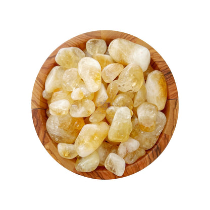 A wooden bowl filled with Citrine Tumbled Stones of various sizes. The stones, translucent with a light yellow hue, symbolize manifestation and prosperity. The wood grain of the bowl adds a natural touch to the overall composition against a plain white background.