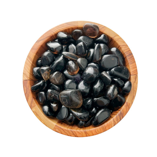 A wooden bowl filled with polished Dark Smoky Quartz Tumbled Stones, arranged neatly and gleaming under the light, is set against a plain white background. These stones are known for their grounding and protective energies.