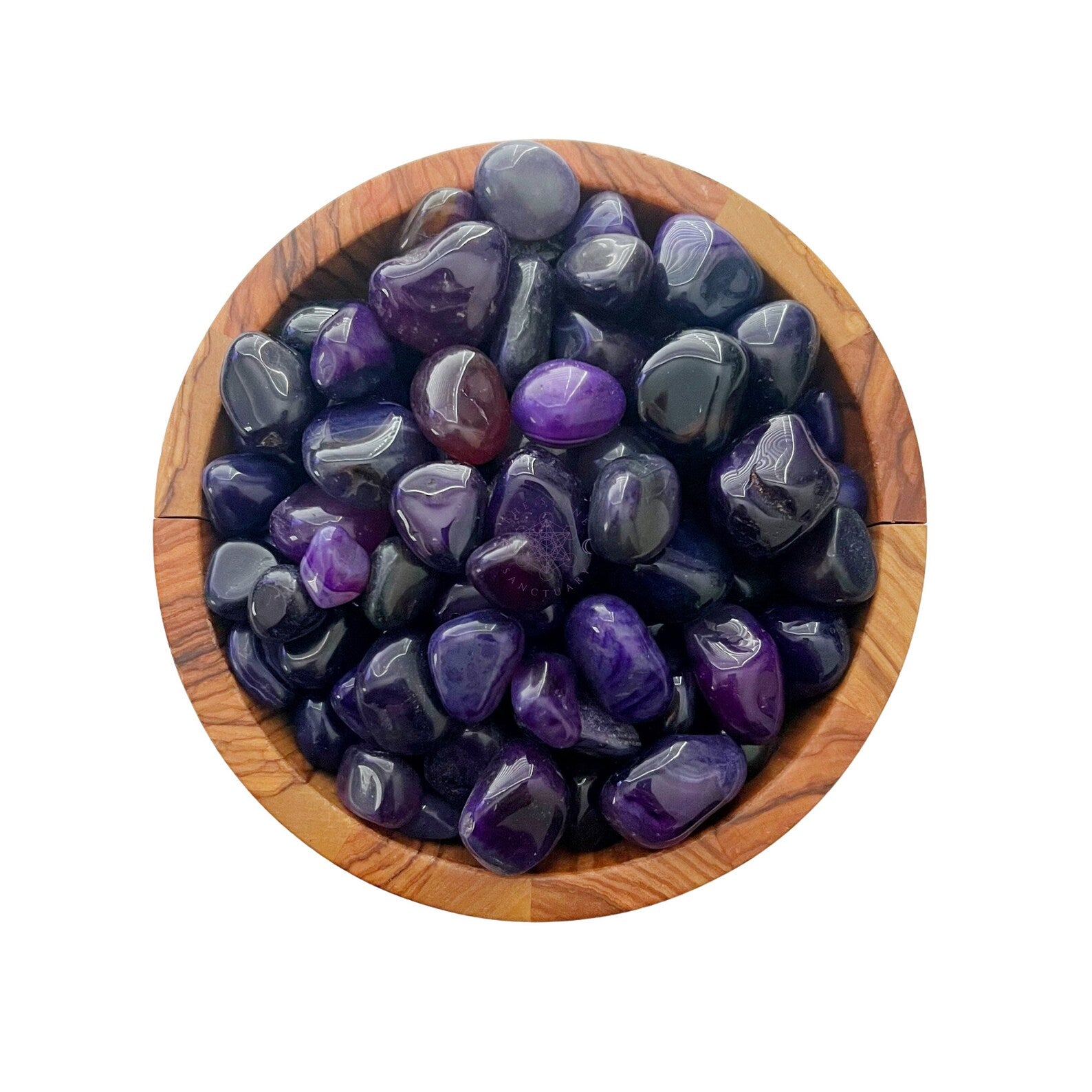 A wooden bowl filled with polished Purple Agate Tumbled Stones. The tumbled stones vary slightly in shade and size, glistening with a shiny, smooth surface that radiates spiritual energy. The white background highlights the vivid purple and the natural wood grain of the bowl.