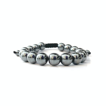 A 10mm Hematite Beaded Bracelet made of polished metallic beads, threaded onto an adjustable black cord. The shiny beads reflect light, creating a sleek and modern appearance with universal appeal. The bracelet is coiled into a circular shape, with the black cord ends visible at the top.