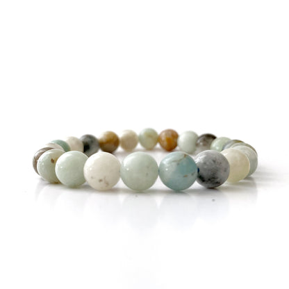 A beaded bracelet made of round, polished beads in various soothing hues, including shades of white, light blue, tan, grey, and mint green. This 8mm Amazonite Beaded Bracelet is arranged in a circle and set against a clean, white background.