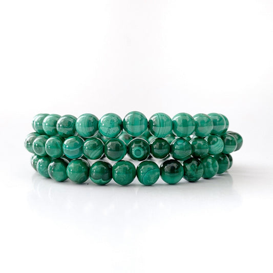 A stack of three 8mm Genuine Malachite Beaded Bracelets displayed on a plain white background. Each bracelet features round, polished beads with natural light and dark green banding and swirls, characteristic of this malachite protection stone.