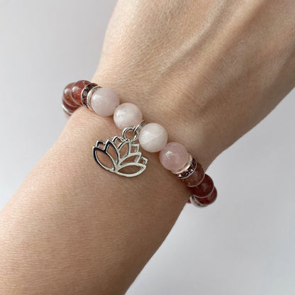 8mm Rose & Strawberry Quartz Beaded Bracelet w/Lotus Charm featuring alternating light pink and brownish-red beads with silver spacers. Accented with a lotus flower charm in silver, the design showcases Strawberry Quartz and Rose Quartz beads, displayed elegantly on a white background.