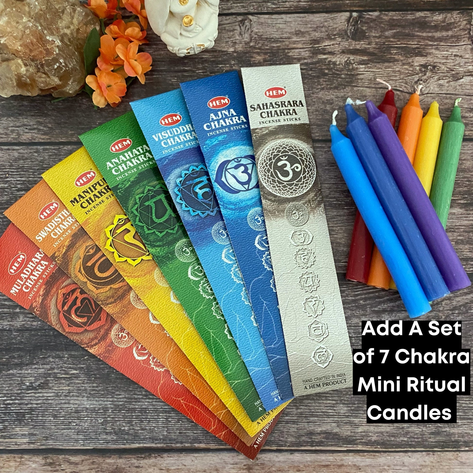 A 7 Chakra Incense Set arranged in a fan shape on a wooden surface. Each pack is colored differently, representing the chakras for meditation and Chakra balancing: Muladhara (red), Svadhisthana (orange), Manipura (yellow), Anahata (green), Vishuddha (blue), Ajna (indigo), and Sahasrara (purple).