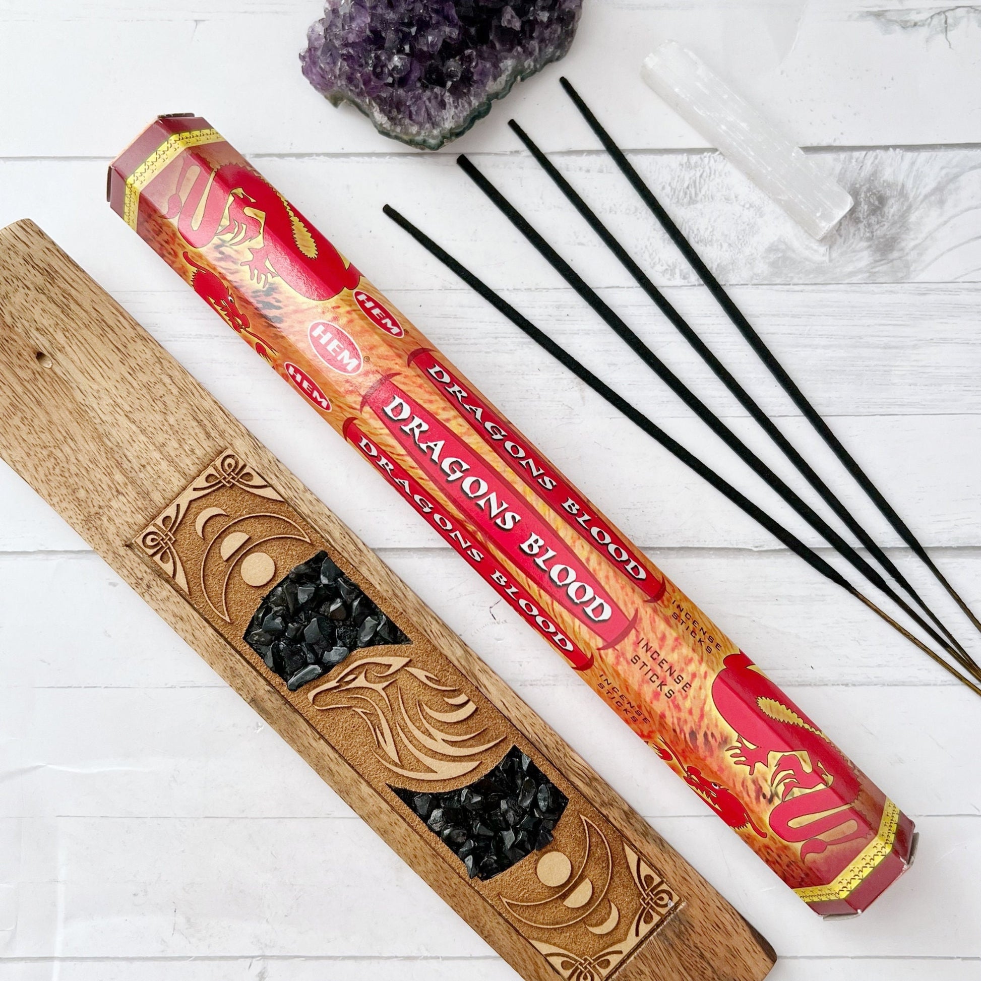 Image of a box and a tube of Dragon's Blood Incense Sticks, perfect for meditation yoga. The packaging features a red design with yellow dragons and a textured background. The rectangular box and cylindrical tube clearly showcase the product name, ideal for enhancing your witchcraft Wicca rituals.