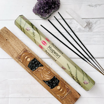 Image showing two boxes of Mugwort Incense Sticks, perfect for meditation. The light green boxes feature images of mugwort plants and bees. The larger box is on the left, while the smaller stands upright on the right. The HEM logo is present with the text "Mugwort Aromatic Incense Sticks.