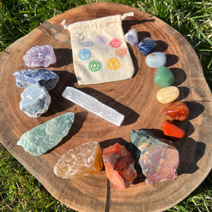 An image of a 15Pc Rough & Tumbled Beginner Chakra Crystal Kit featuring various rough and tumbled healing crystals. The crystals, perfect for chakra healing and energy balance, are labeled as Amethyst, Sodalite, Angelite, Green Aventurine, Yellow Calcite, Carnelian, Jasper, and Selenite Stick. Each crystal's properties are listed below.