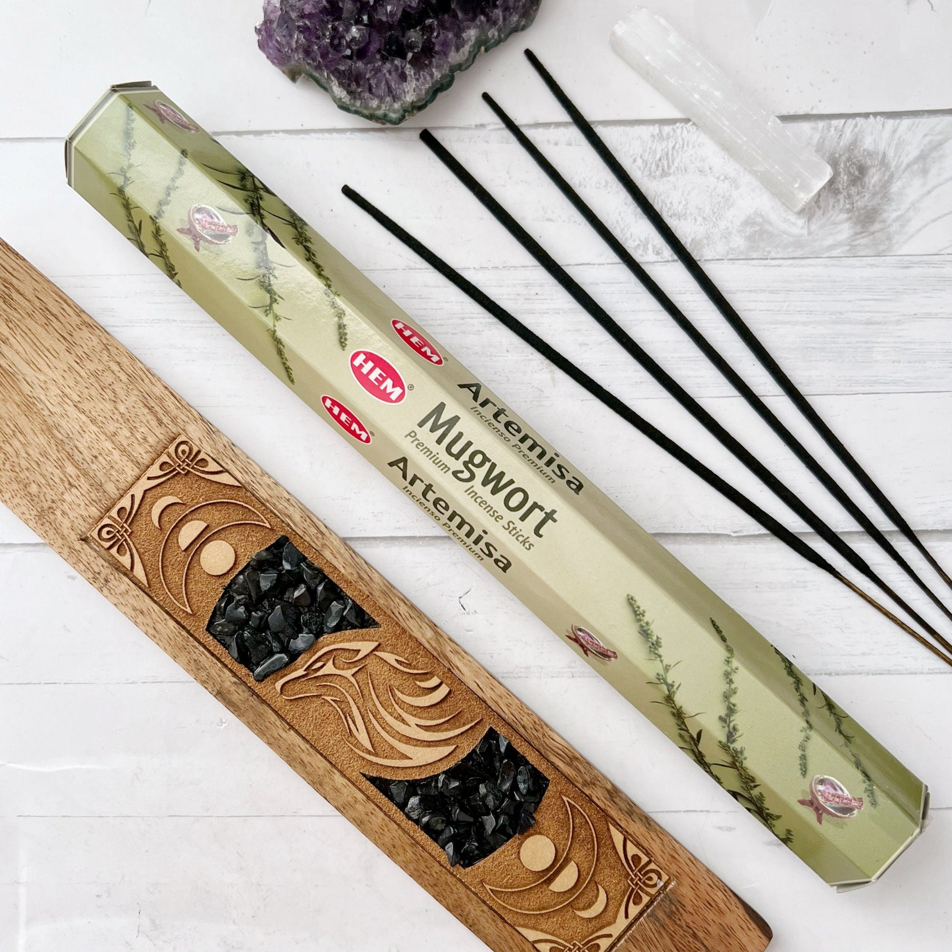 Image showing two boxes of Mugwort Incense Sticks, perfect for meditation. The light green boxes feature images of mugwort plants and bees. The larger box is on the left, while the smaller stands upright on the right. The HEM logo is present with the text "Mugwort Aromatic Incense Sticks.