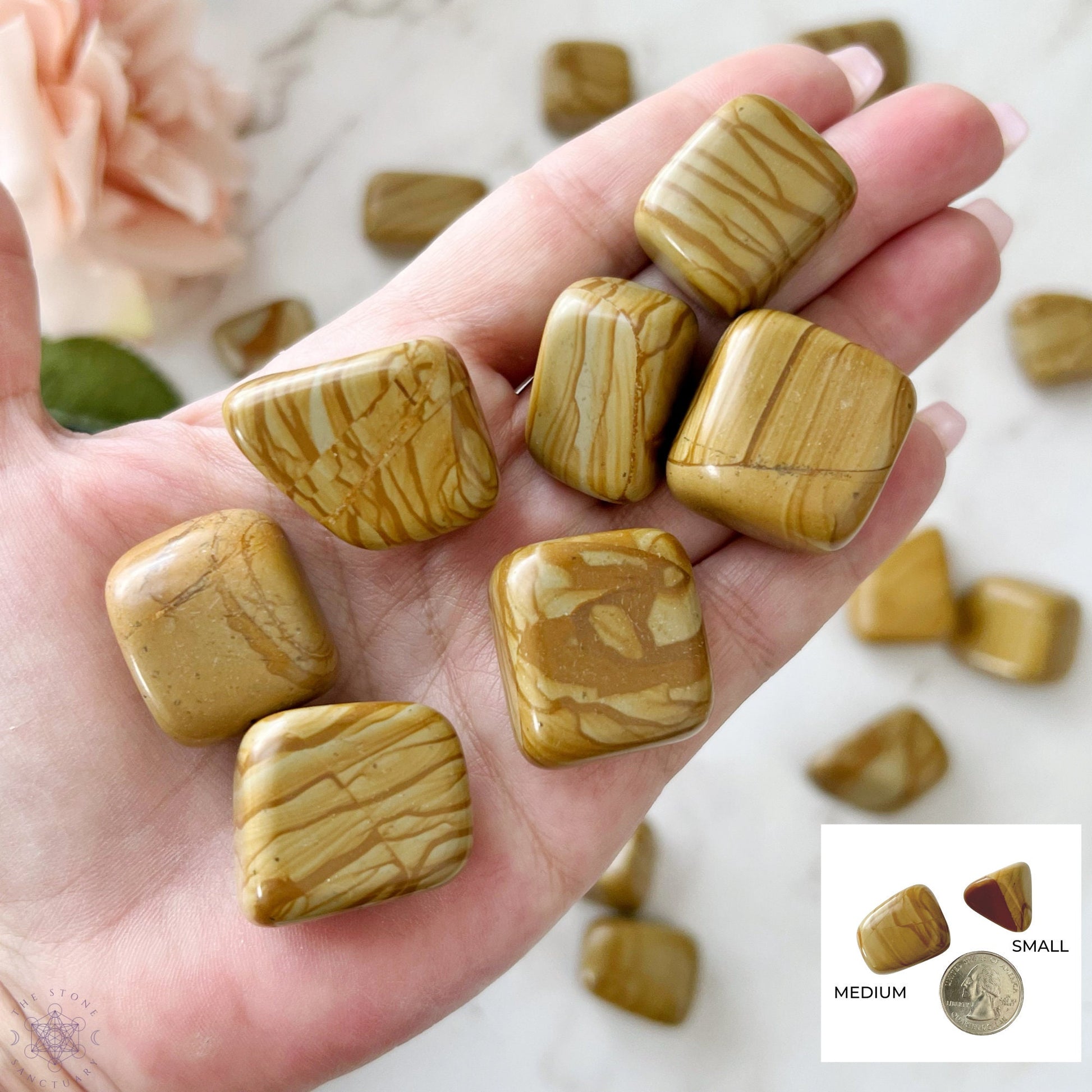 A wooden bowl filled with polished, light brown Brown Walnut Jasper Tumbled Stones with natural patterns and variations. The grounding stones are smooth and rounded, creating a visually appealing and uniform texture within the bowl. The white background highlights the bowl and its contents perfectly.