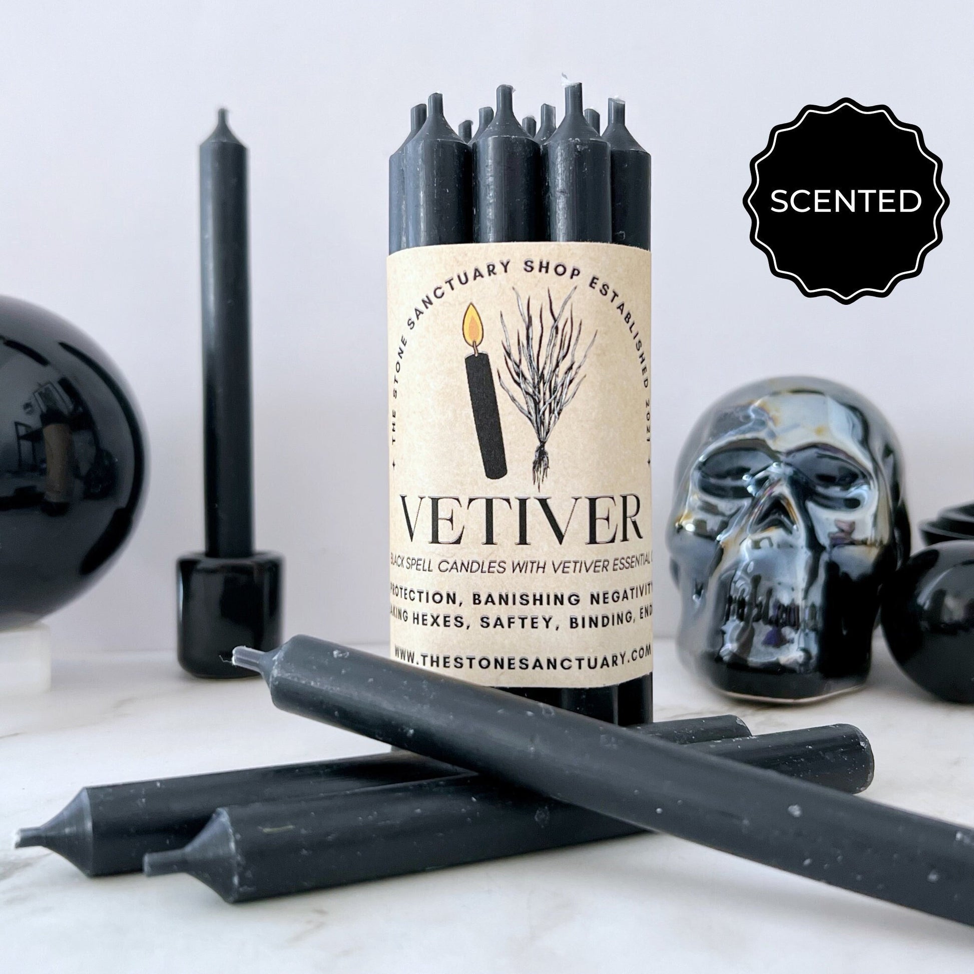 A bundle of black, 5" Vetiver Scented Black Chime Candles labeled "Vetiver" for protection and banishing negativity from The Stone Sanctuary Shop. Infused with Vetiver essential oil, the candles are displayed alongside other black candles, a black skull, and decorative black items in the background—perfect for spiritual practices.