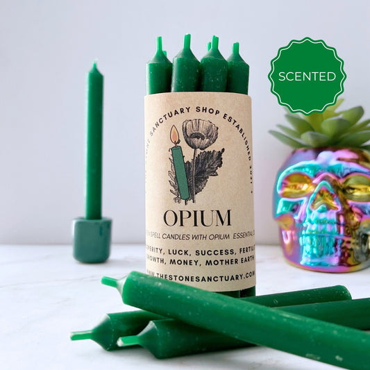 A bundle of 5" Opium Scented Green Chime Candles from The Stone Sanctuary Shop. These 5" Opium Scented Green Chime Candles are associated with properties such as prosperity, luck, success, and more. The background includes a lit green candle and a colorful skull decoration.